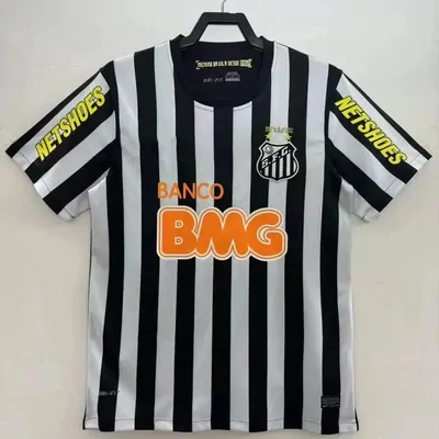 A black and white vertically striped football shirt on a wire hanger, with an orange sponsor print across the chest and a shield-shaped crest at the right chest.